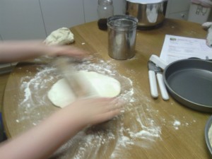 Rolling out the dough to fit our round pans!